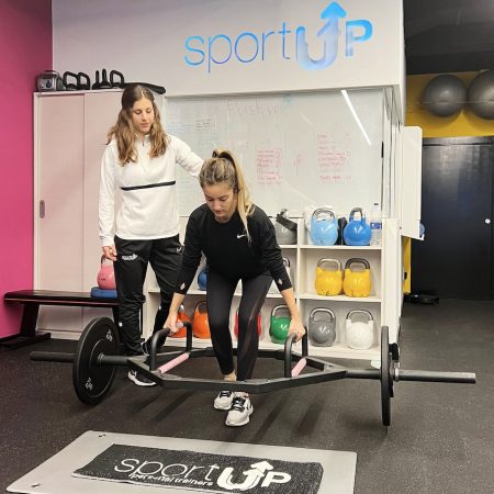 Entrenadora supervisando a una chica levantando unas pesas